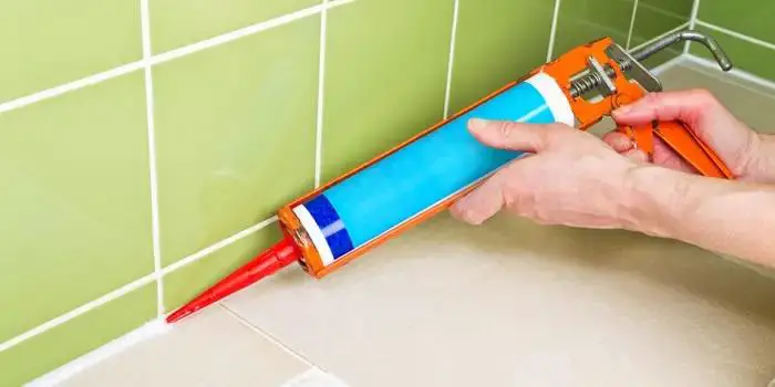 a Person Using Caulk Gun | How to Close the Gap Between Tub and Floor 